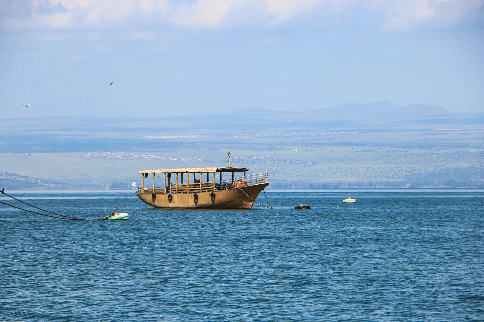 A boat floats on calm water near the horizon