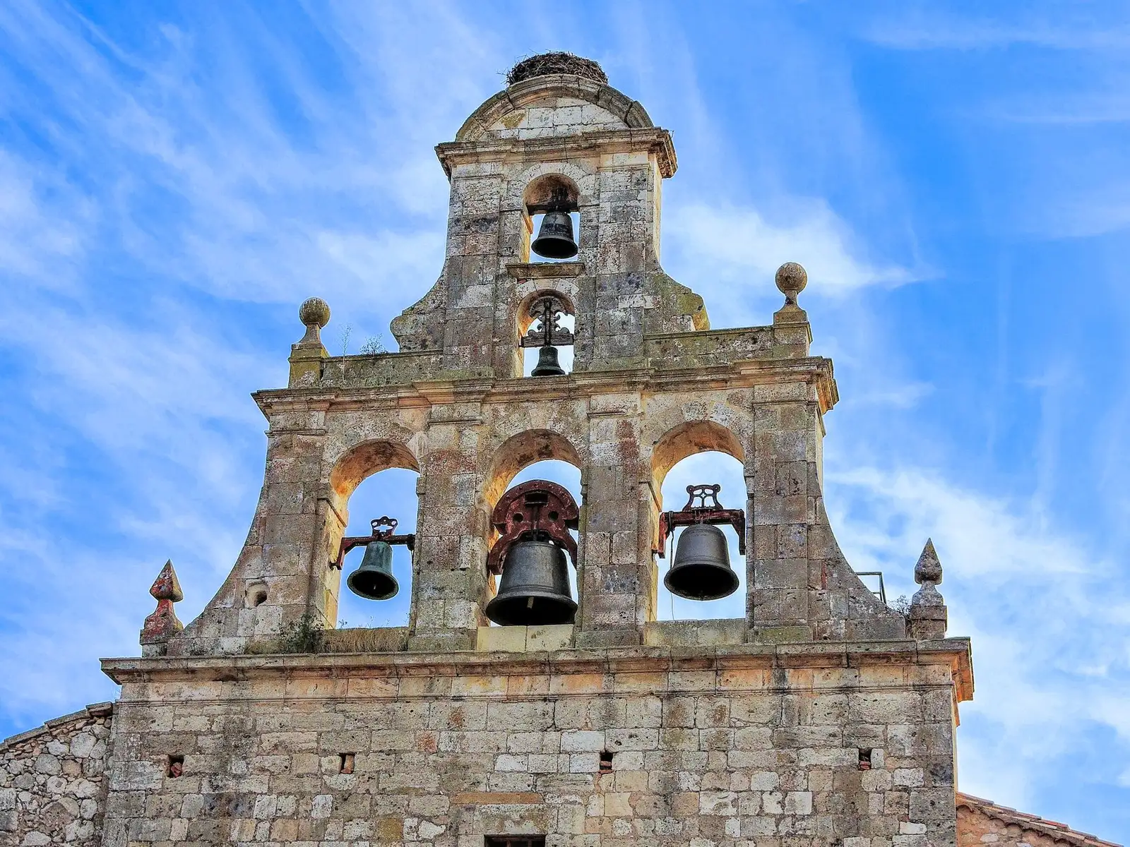 Historic gothic bell tower against blue sky in Maderuelo, Spain, showcasing stone architecture and religious heritage.